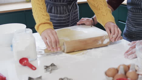 midsection of diverse couple baking christmas cookies in kitchen at home, in slow motion