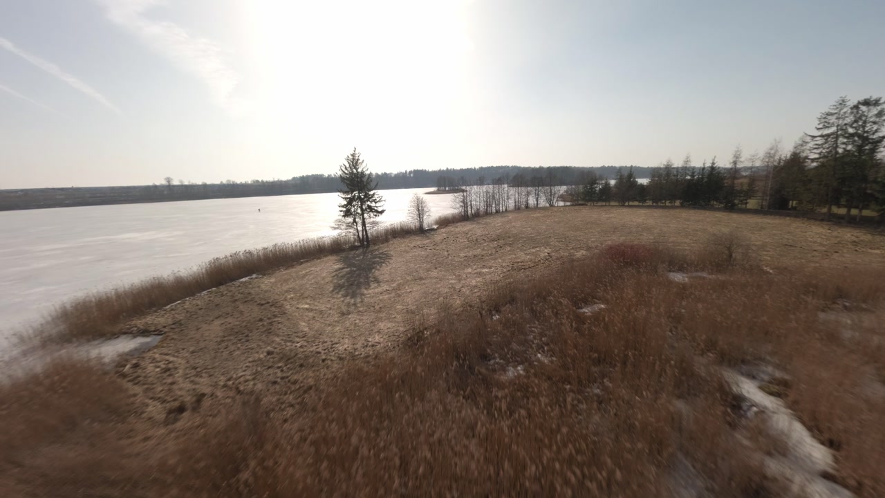 Drone flying over frozen lakeshore in Masurian Lake District