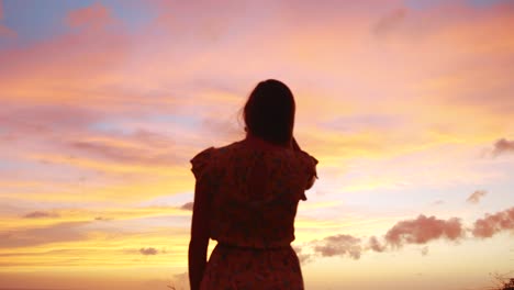 hermosa joven con un vestido amarillo mirando la puesta de sol