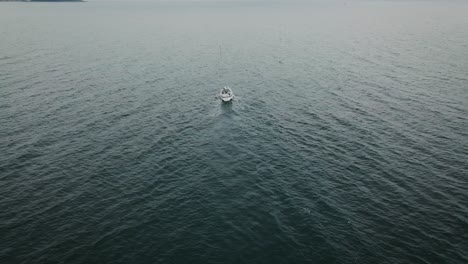 tilting aerial view from following behind sailboat at sea