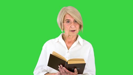 beautiful senior woman reading aloud from a book on a green screen, chroma key