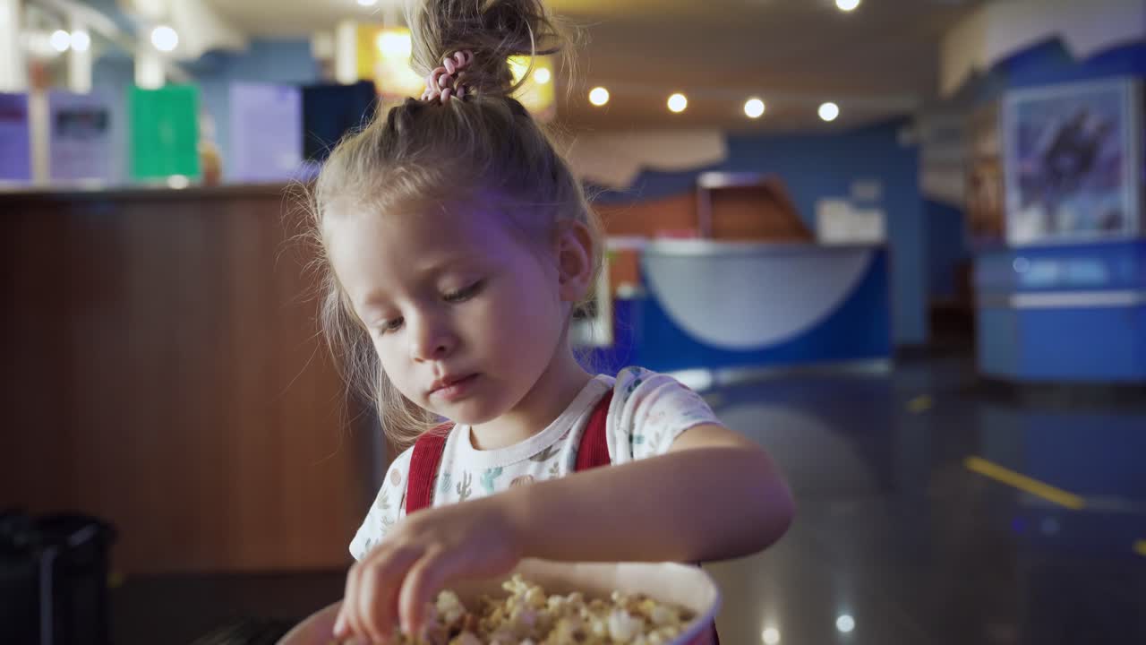 una niña comiendo palomitas de maíz en un cine