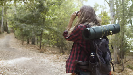 menina jovem mochileiro com câmera tirando fotos da floresta