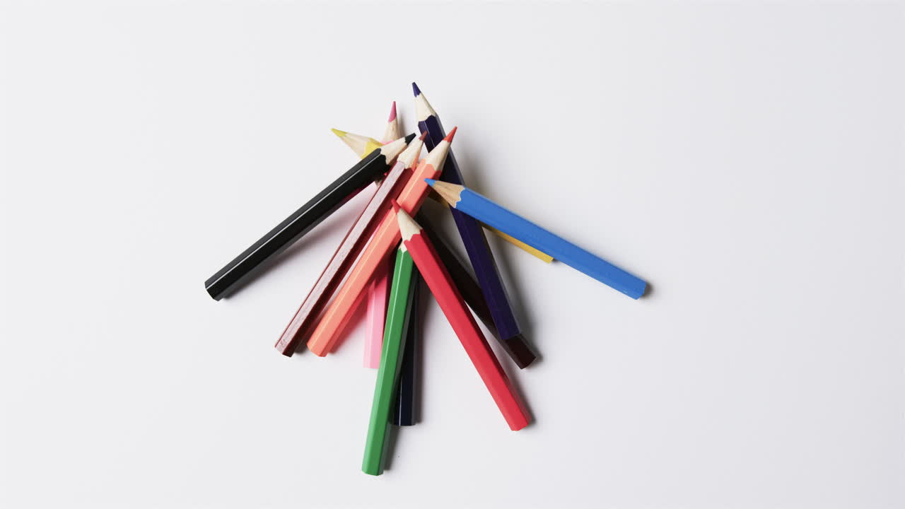 vista aérea de lápices de colores sobre fondo blanco, en cámara lenta