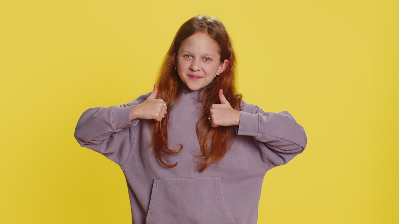 Happy preteen child girl kid looking approvingly at camera showing thumbs up like positive sign