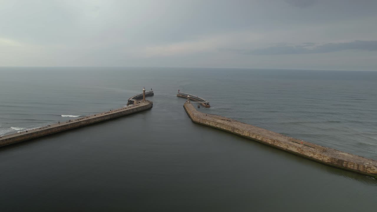 Aerial shot of the east and west piers at the entrance to the seaside town of Whitby in Yorkshire, Northern England