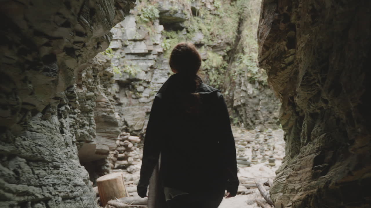 Silhouette walking towards light at the end of a dark cave