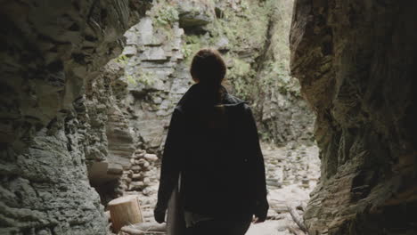 silhouette walking towards light at the end of a dark cave