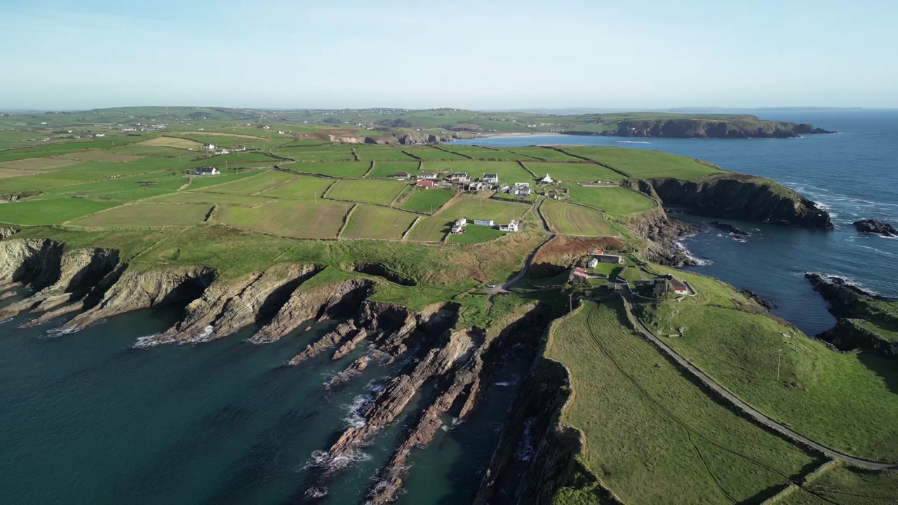 Landbrugsjord og vild natur, afsløring fra luften, drone flyver baglæns over Galley Head forbjerg med barsk kyst og roligt Atlanterhav