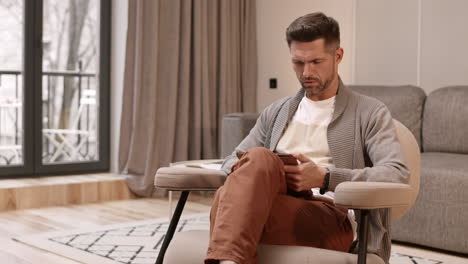man sitting in armchair with tablet computer