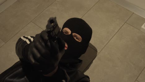 masked man lying on the ground and aiming upwards