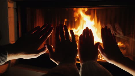 Young-Couple-Warms-Their-Hands-By-The-Fireplace-Romantic-Evening-Together