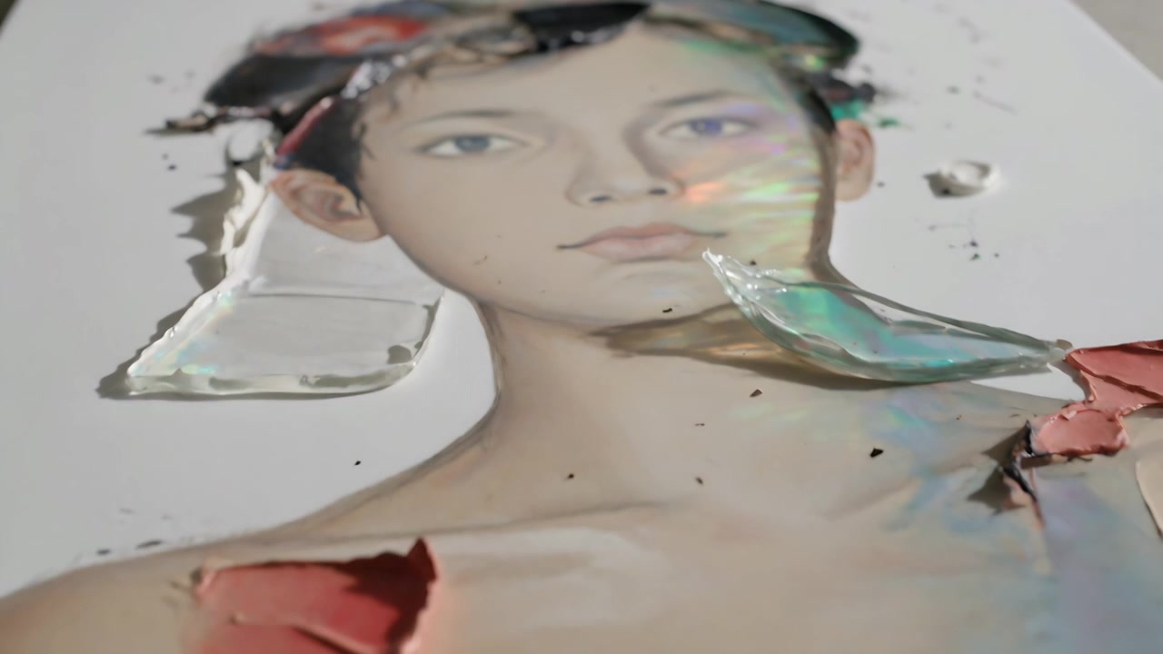 Tilting camera revealing portrait on art desk to show bare shoulder, texture, iridescent fragment