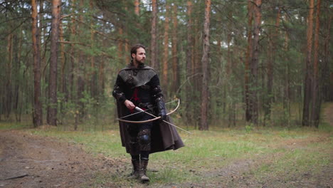 knight in armor walks through forest with bow