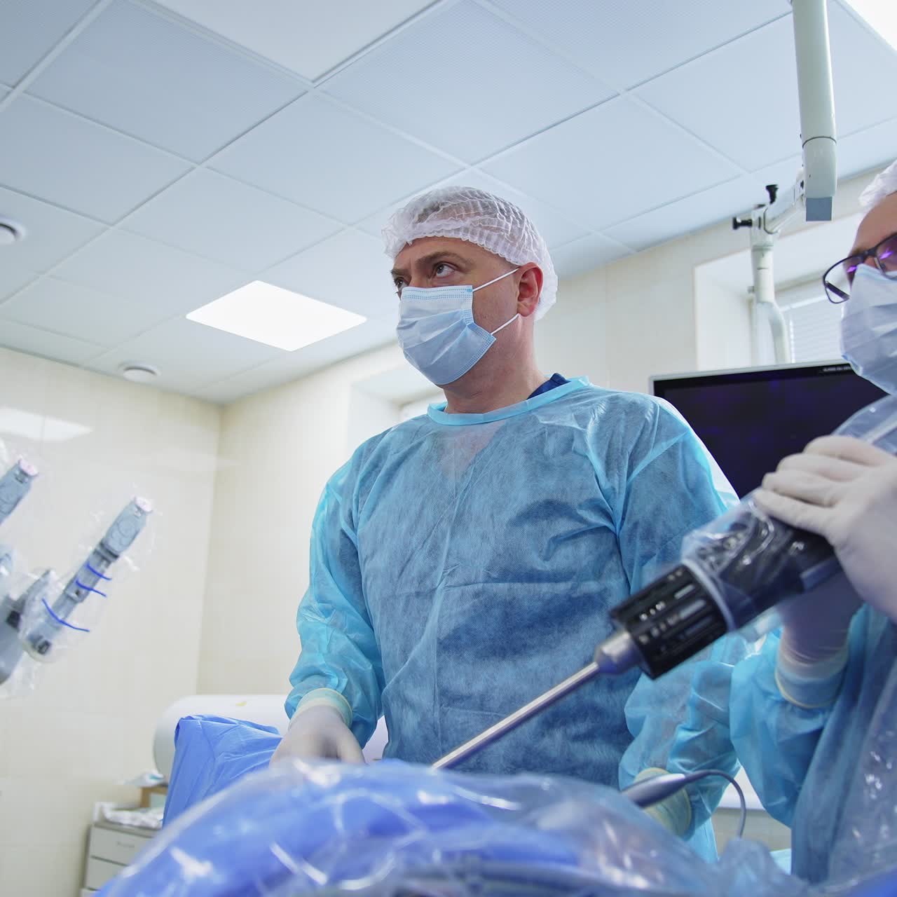 Focused and tensed doctors use innovative tools while operating and look at the screen intently. Medical professionals concentrated on works