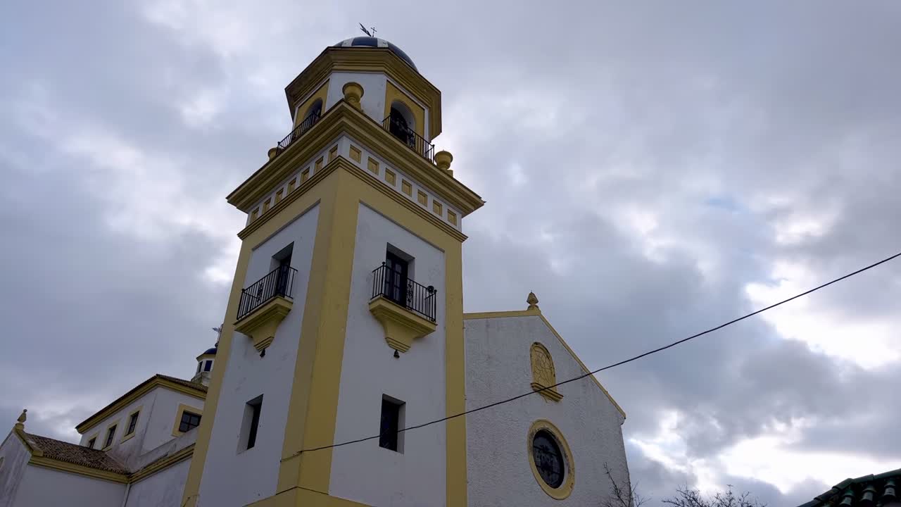 Time-lapse of church bell tower in Spain with cloudy sky, serves as a timeless call to worship and a reminder of the enduring traditions that have shaped Spain's cultural identity
