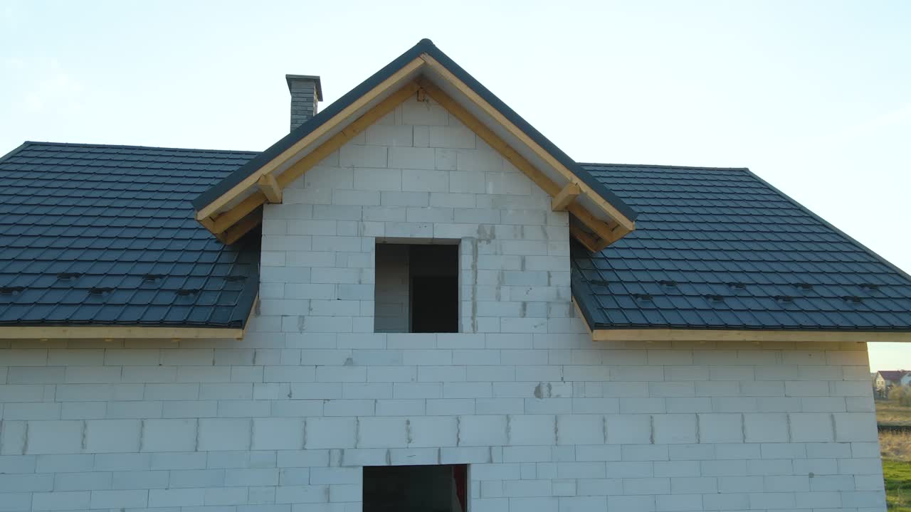 vista aérea de una casa inacabada con paredes de hormigón ligero aireado y marco de techo de madera cubierto con azulejos metálicos en construcción