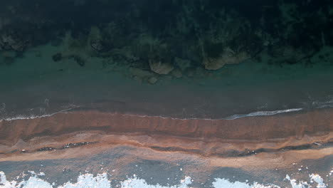 Drohnenaufnahme-Mit-Direktem-Blick-Auf-Einen-Strand-Im-Frühling,-Wenn-Noch-Etwas-Schnee-Auf-Dem-Boden-Liegt