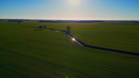 Trinchera-De-Agua-Rodeada-De-Interminables-Campos-Agrícolas-Verdes,-Vista-Aérea-De-Drones