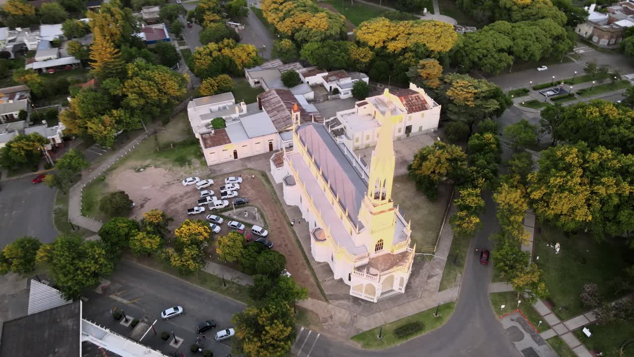 descenso aéreo hermosa iglesia neogótica rodeada de árboles en medio de la ciudad rural de santa elisa, entre rios, argentina