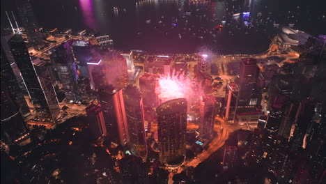 fireworks over hong kong skyline at night with victoria harbour and tsim sha tsui in background - tilt up