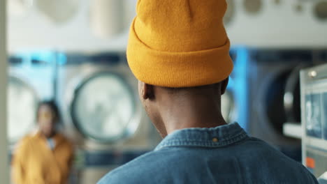 rear of young guy meeting girl and hugging at laundry service room