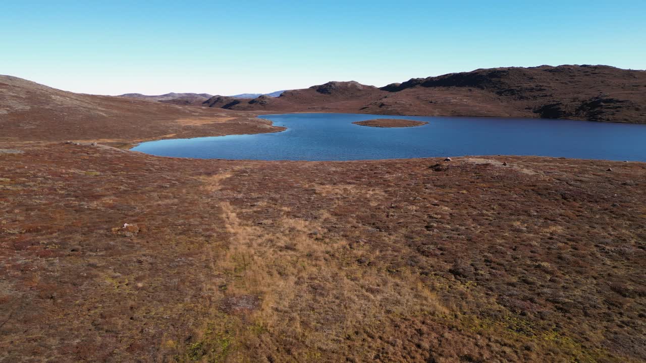 Flyover golden amber summer tundra lakes in barren Greenland arctic