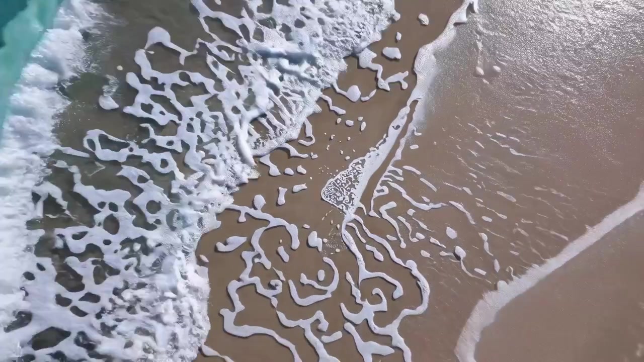Aerial View of Ocean Waves Gently Washing onto Sandy Beach
