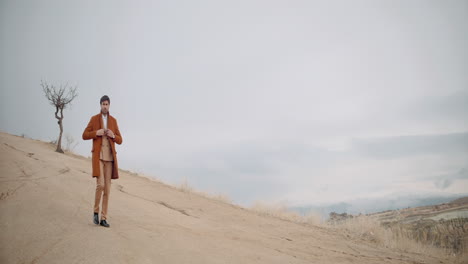 man in a brown suit on a hilltop