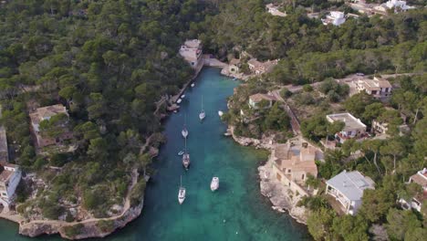 tilt up shot of famous port de cala figuera with yachts in water, aerial