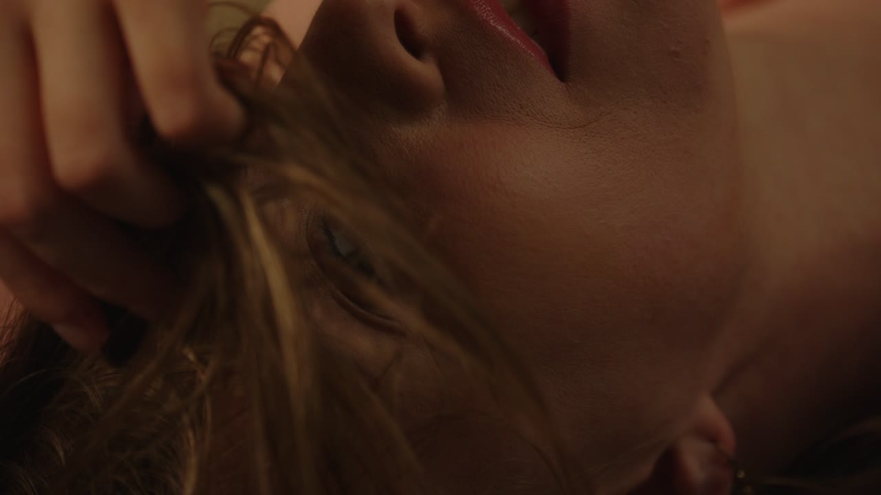 Beautiful macro of an enticing woman sensually looking at the camera and playing with her hair in 120fps slow motion