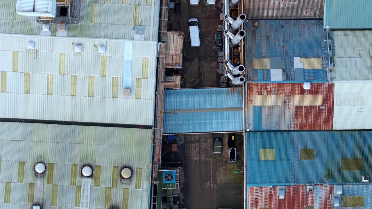 90 degree overhead aerial drone shot of intricate metal factory roofs and mechanical cooling fan arrays