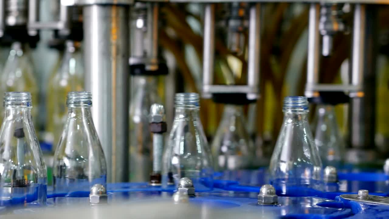 línea de máquina automática para llenar agua en una botella de vidrio. embotellado de bebidas a base de hierbas en botellas de vidrios. producción de agua potable y bebidas.