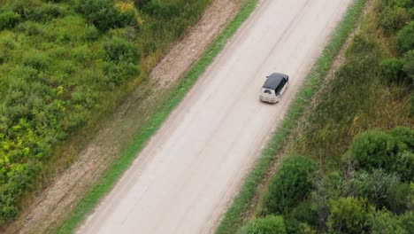 drone shot - following a minivan driving on an dirt road