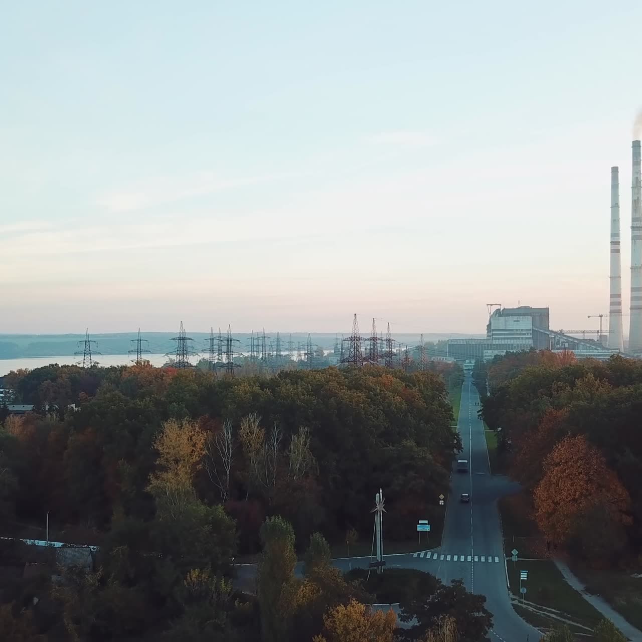 view of the power station with two pipes and with road to it with the planting of trees near the river. Aerial view