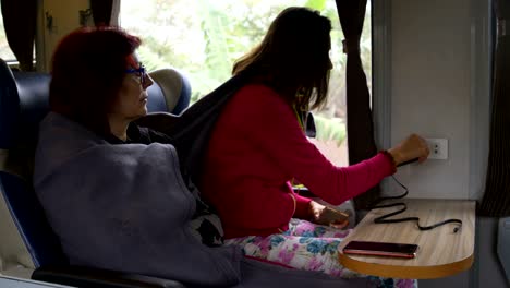 a woman is charging a phone in a train