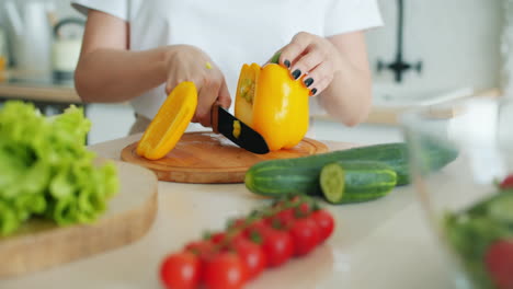 woman cutting a yellow pepper in a kitchen