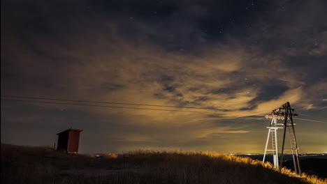 night sky timelapse of a hilltop with a ski lift montain station