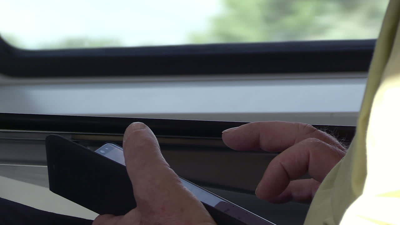 primer plano de la mano de un hombre usando un teléfono inteligente en un tren en movimiento