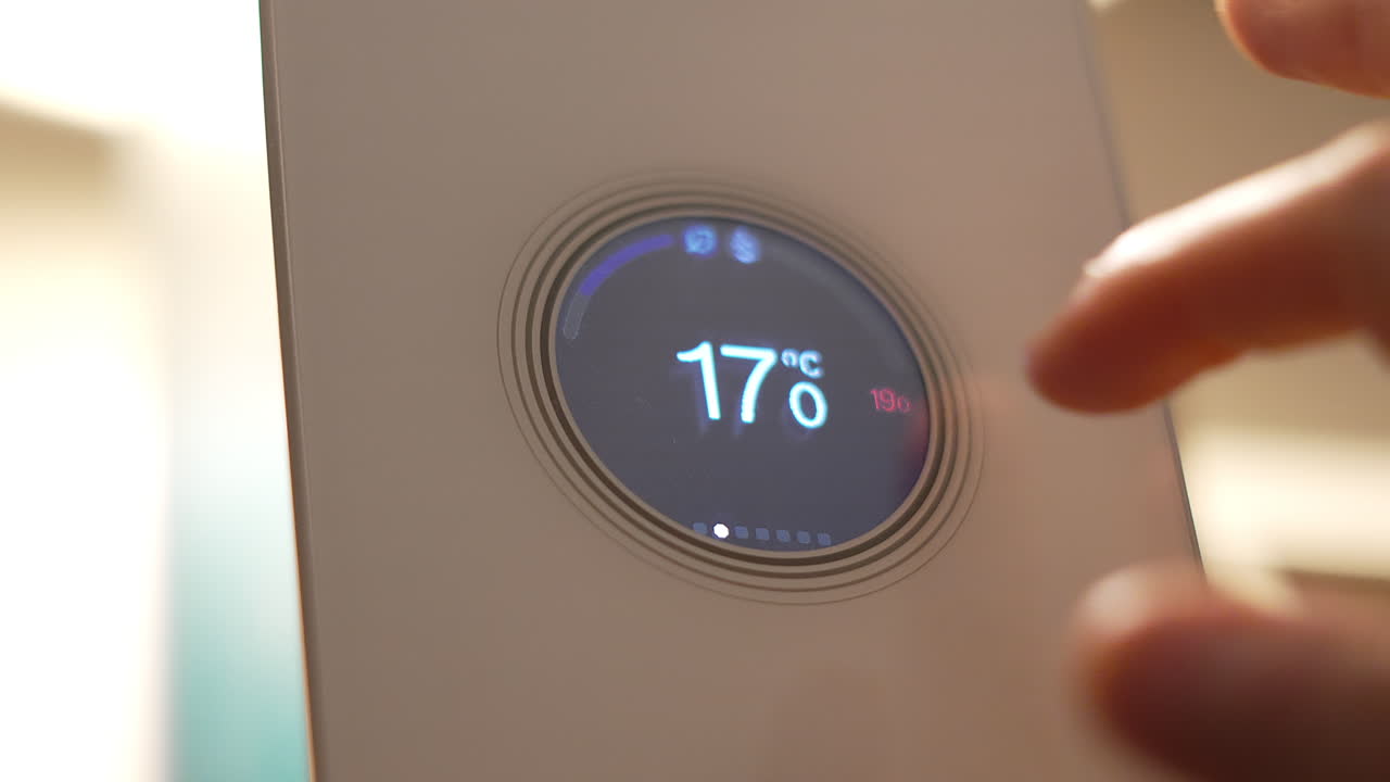 Close Up of Finger Adjusting Thermostat from 17°C to 19°C to Heat House During Winter Months. Smart Home Digital Device Being Used Via Internet to Communicate Information