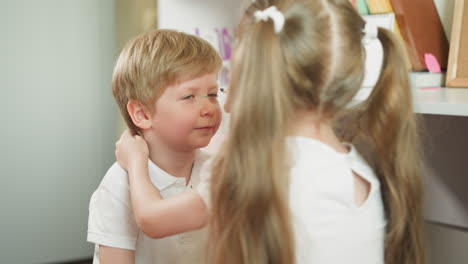 blonde schoolgirl draws circles around younger brother eyes