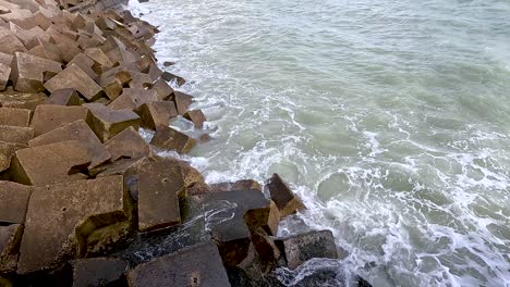 waves hitting concrete blocks on the shore