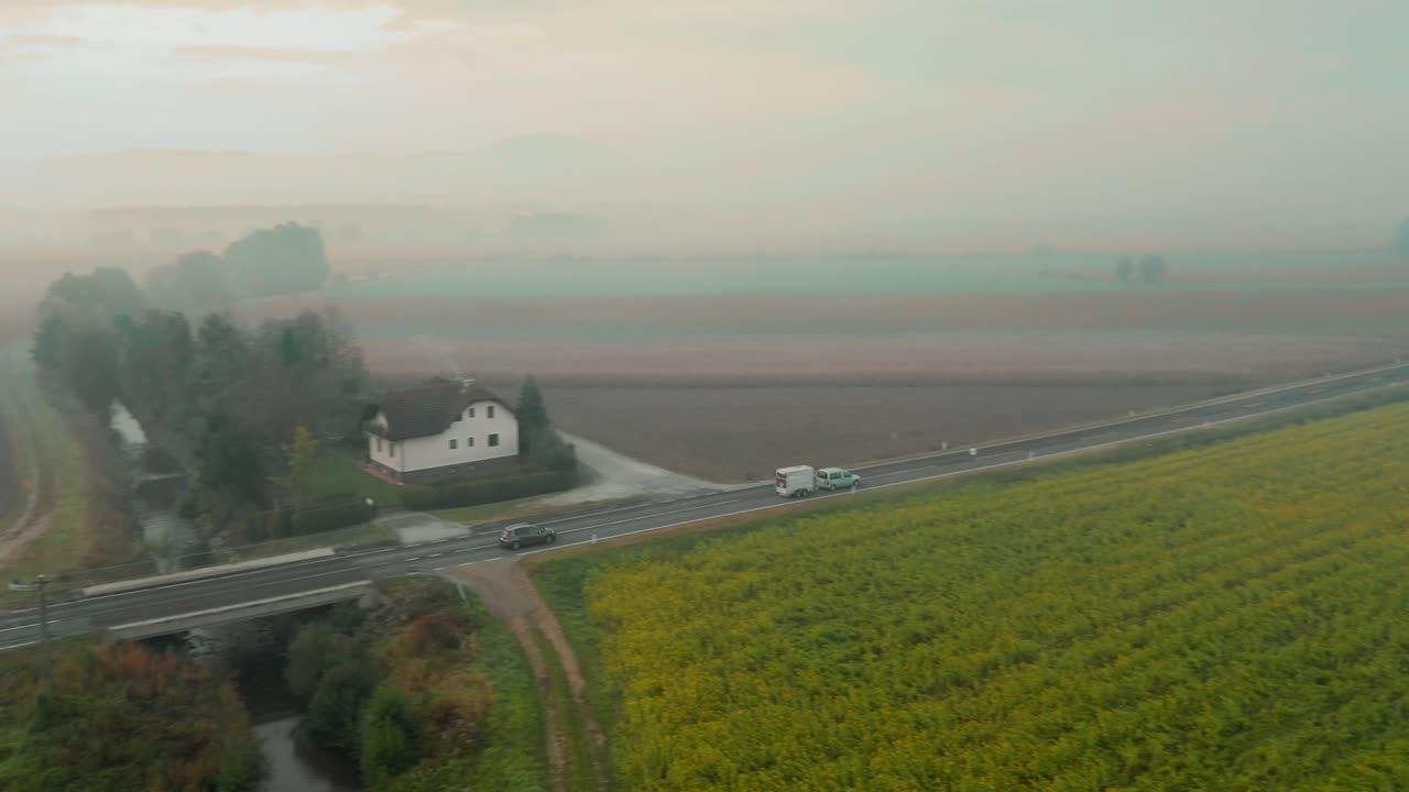 안개 낀 가을 아침에 슬로베니아 시골의 농지를 통과하는 도로의 공중 전망