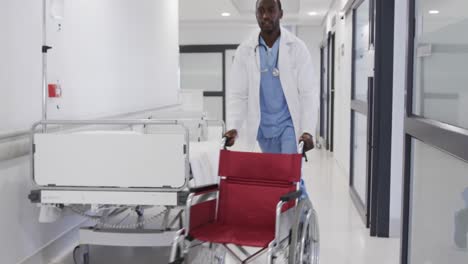 African-american-male-doctor-running-with-wheelchair-in-hospital-corridor,-slow-motion