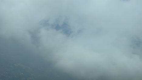 vista aérea desde la cabina de un jet mientras se despelleja a través de capas de nubes durante el descenso al aeropuerto en un giro a la izquierda