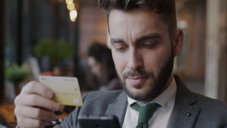 businessman using smartphone and credit card in a cafe