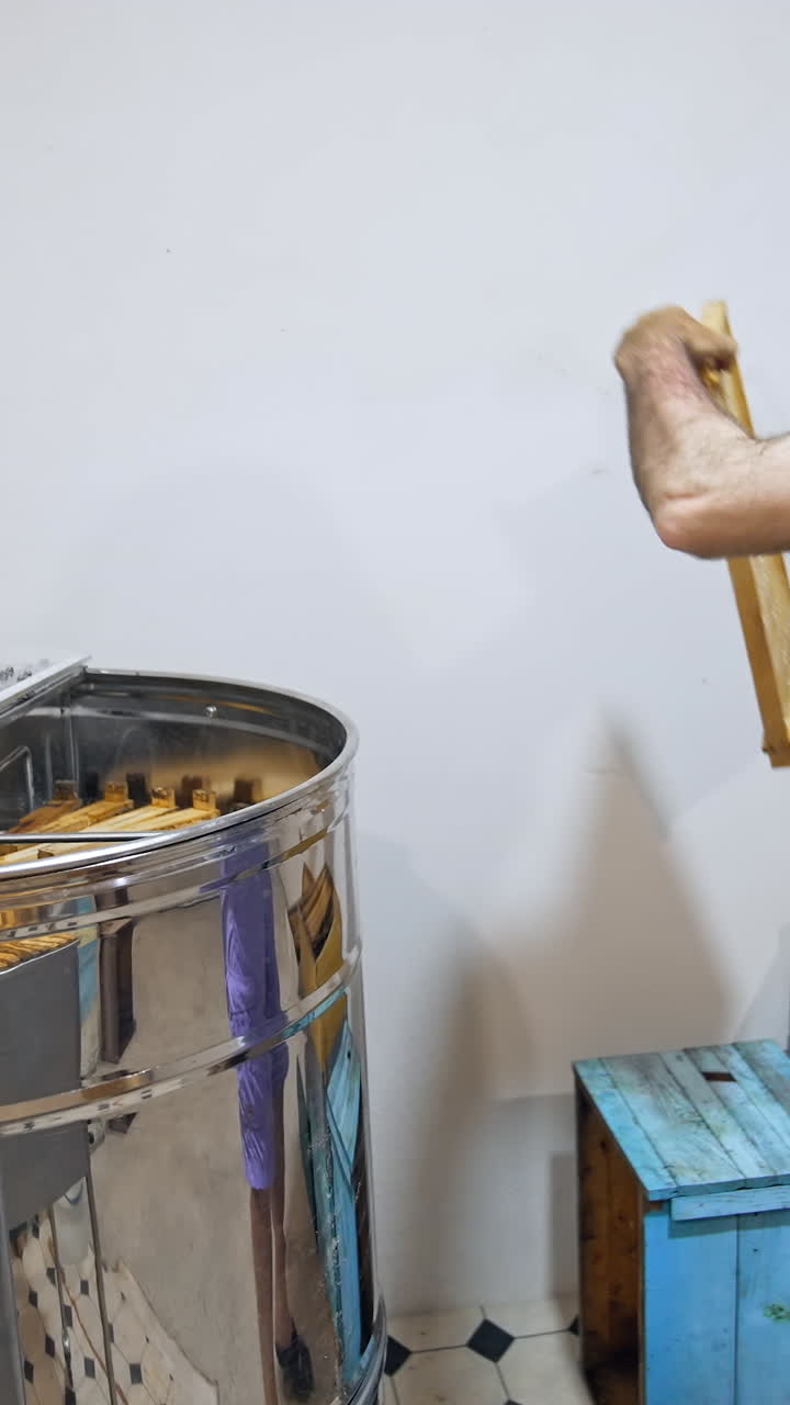 Handsome man working with honey wooden frame. Factory apiarist working with wooden beehives