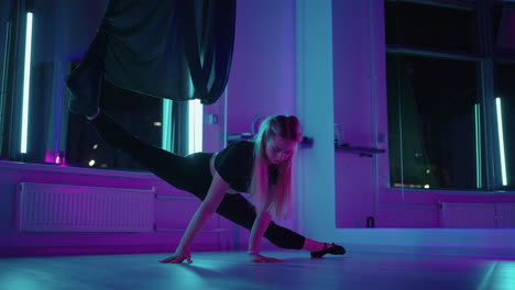 Una-Mujer-Estira-Las-Piernas-Haciendo-Una-Posición-Dividida-En-Una-Clase-De-Yoga-Usando-Una-Hamaca-Para-Volar-yoga