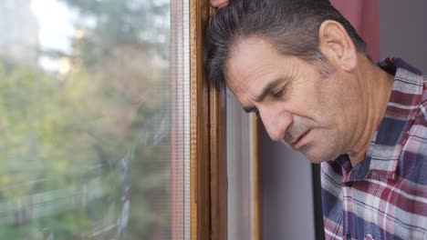 Depressed-man-looks-outside-by-the-window.