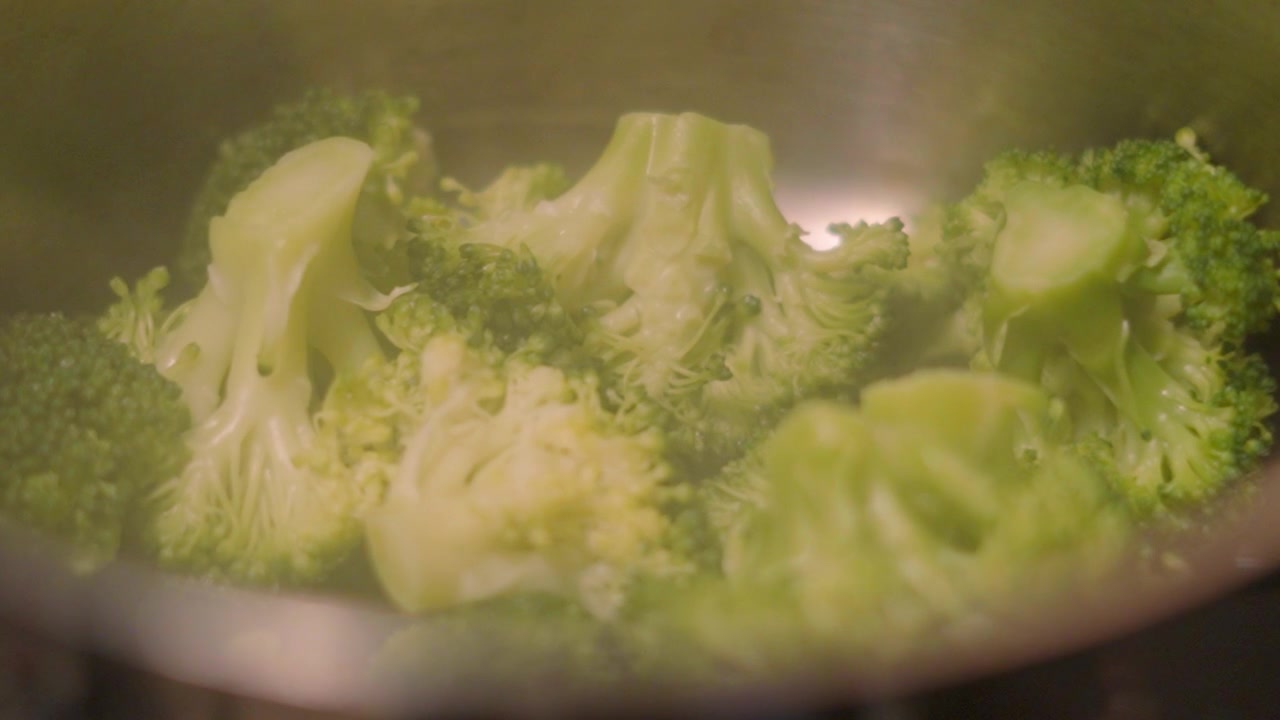 Broccolo verde cotto, sano e nutriente, in pentola con vapore che sale delicatamente in slow motion 4K